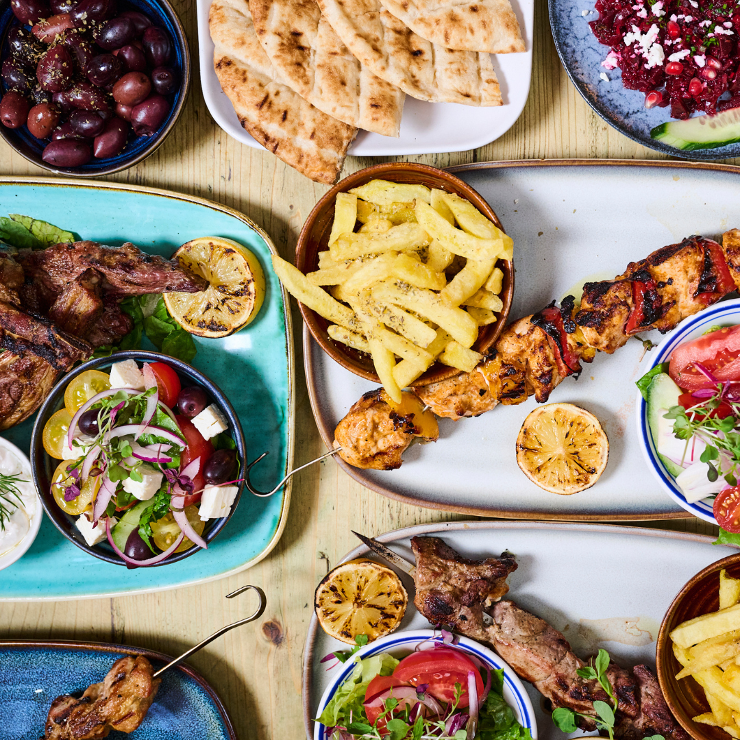A table spread with grilled meats, dips, pitta and salads at Nonòs Judd Street